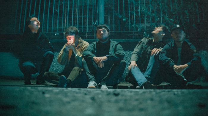 Members of the band 'Vida' sitting on a kerb